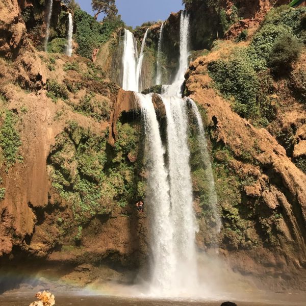 A view of the highest and most beautiful waterfalls in Morocco. Ouzoud. Full flowing into the lake below and surrounded by the characteristic red rock of the region. Moroccan Mystery