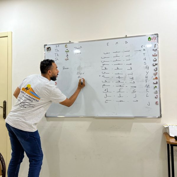 In a classroom with our tour guide. He’s teaching the group how to write their name in Arabic. He’s writing the Arabic alphabet on the whiteboard and explains how the symbols go together and the sounds that they make. Morocco Explored includes this experience. Morocco Explored
