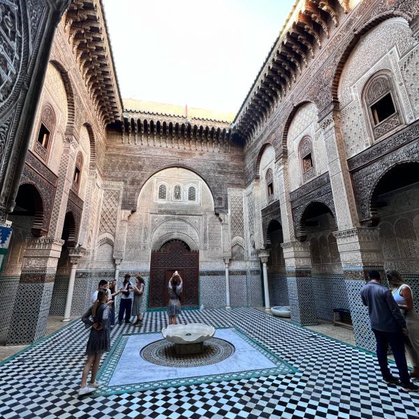 The oldest Madrassa in the world in the ancient medina of the city of Fes. Al Qarawiyin, showing the beautiful zellige and the main courtyard of the university with the fountain. The group are enjoying the opportunity to take some stunning photos of the interior. Morocco Explored