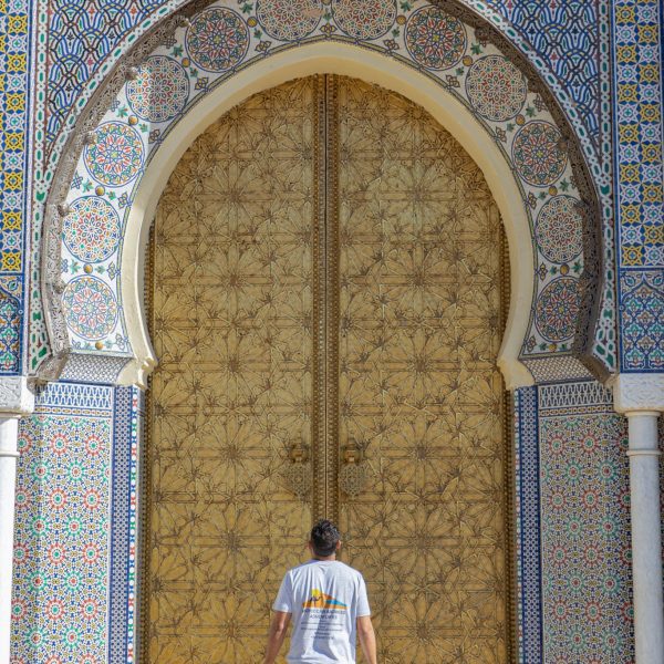 Tour guide standing in front of the ornately decorated main gates to the Royal Palace in the Imperial city of Fes, oldest city in Morocco. Moroccan Mystery