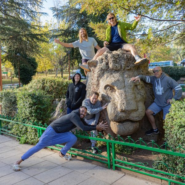 Group of travellers posing on the lion of Ifrane, a statue in the town commemorating the last wild Atlas lion. In the background are the trees of the local park. Morocco Uncovered