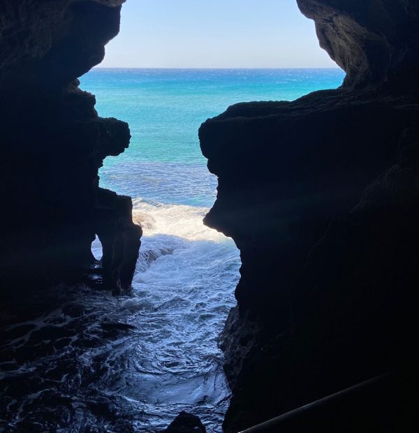 View through the map of Africa in the Cave of Hercules, close to the City of Tangier. The map of Africa is a naturally made hole the shape of the African continent through which we can see the blue sky and the ocean. There are rocks on either side which contrast in colour. Morocco Uncovered